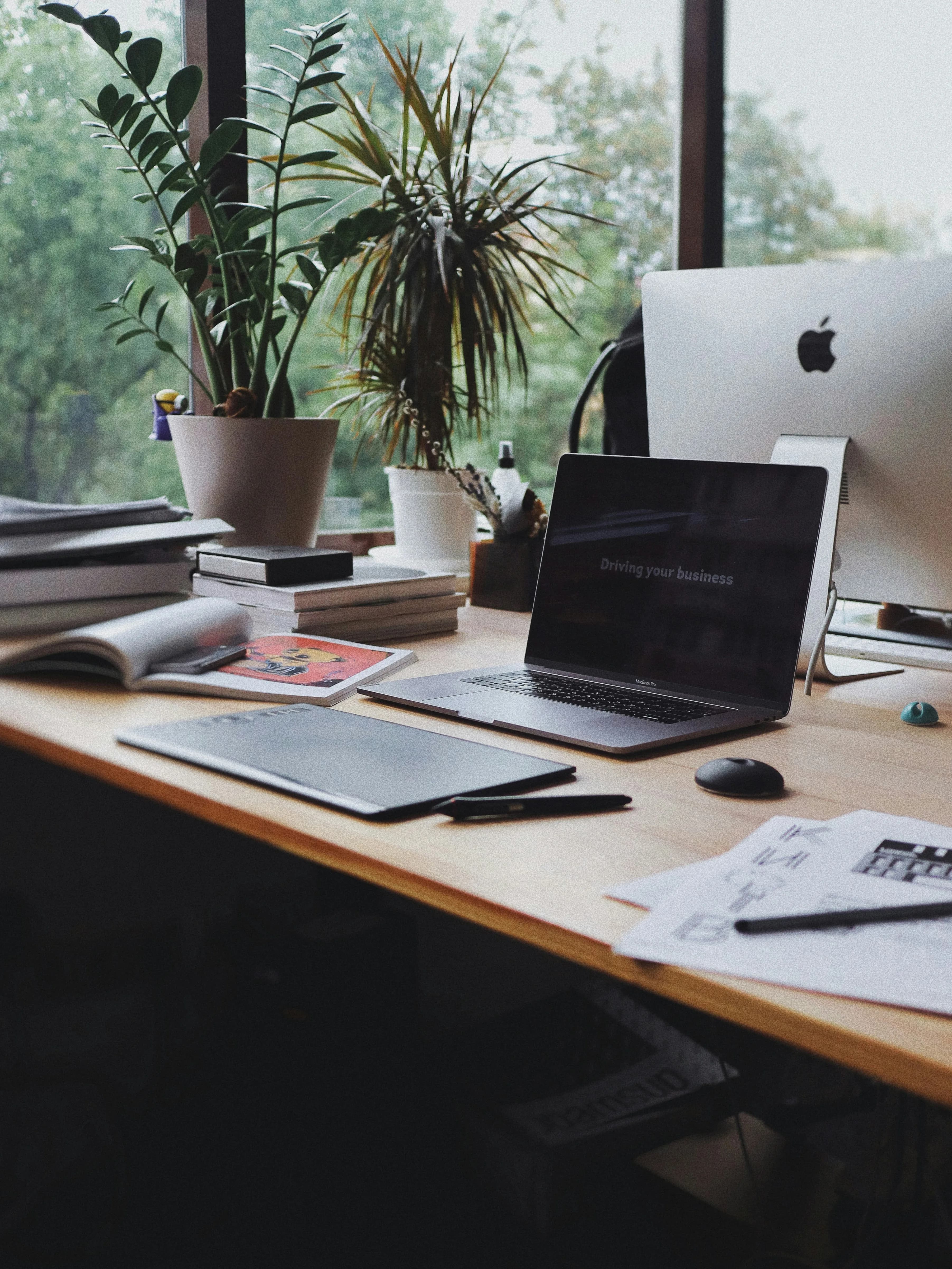 Creative workspace with a laptop, drawing tablet, and design tools by a window